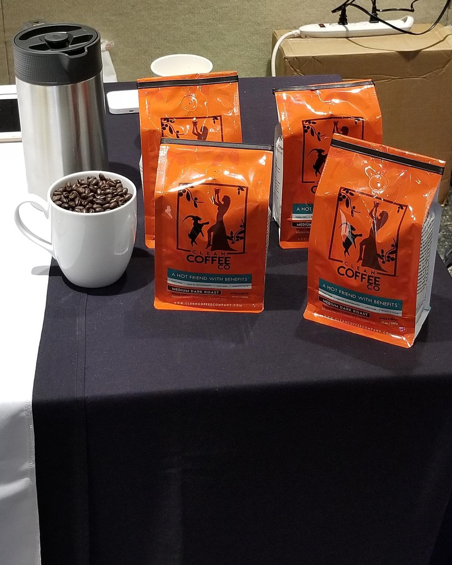 A table with bags of Clean Coffee and a mug of beans.
