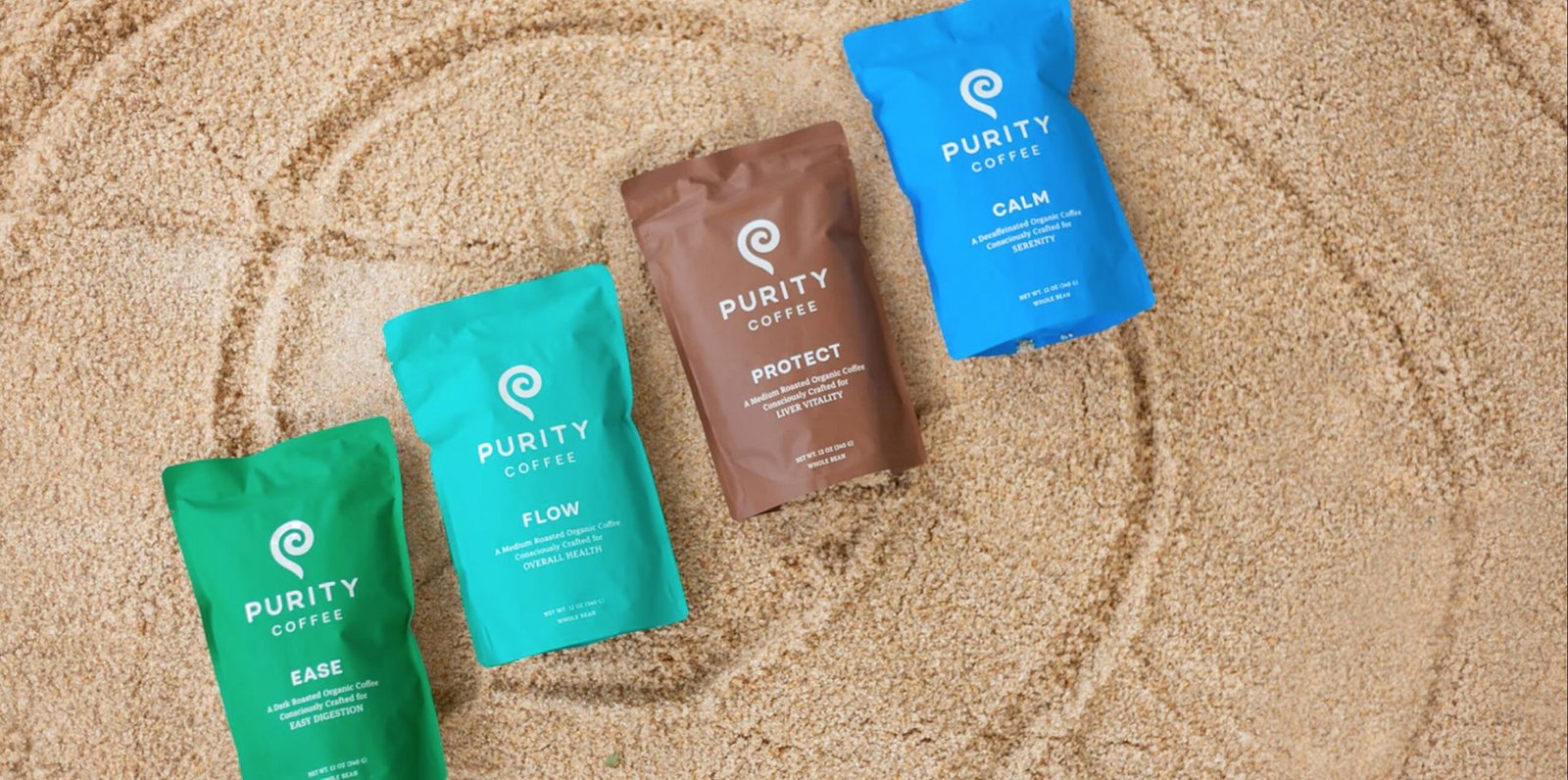 Three bags of Purity coffee lie in the sand.