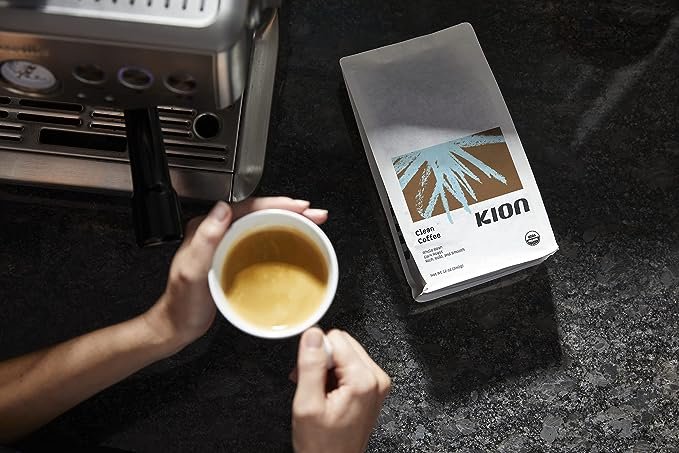 An aerial shot of a hand holding a cup of Kion coffee.