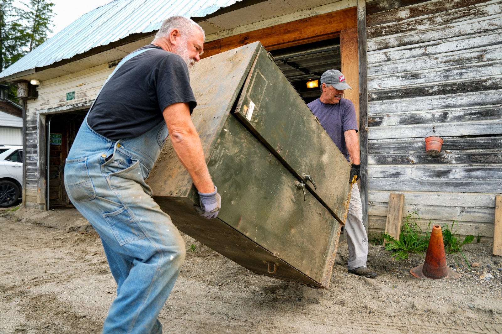 Two men carry a filing cabinet out of a garage in St. Johnsbury, Vermont, after flash flooding in 2024.