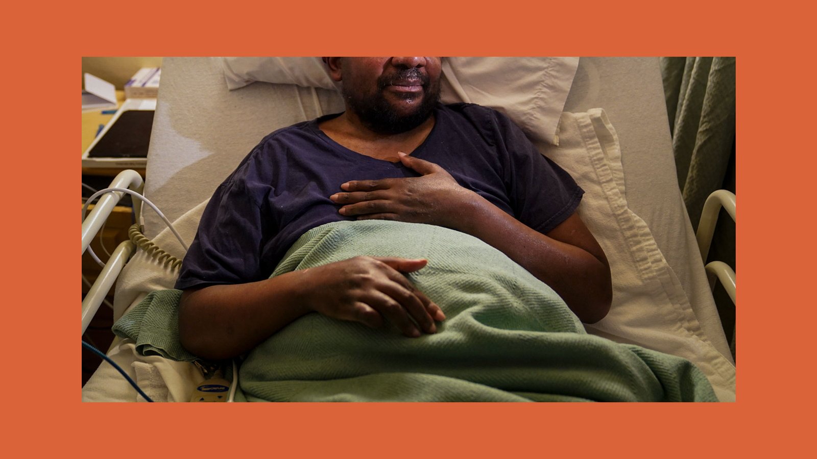 Man sitting in a hospital bed with his hand resting on his chest