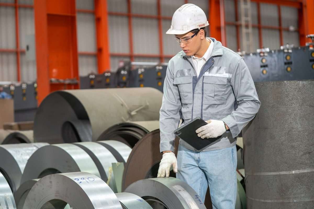 Factory worker inspecting rolls of steel