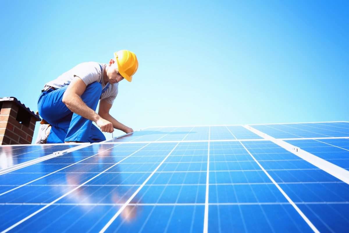 A worker installing solar panels on a rooftop