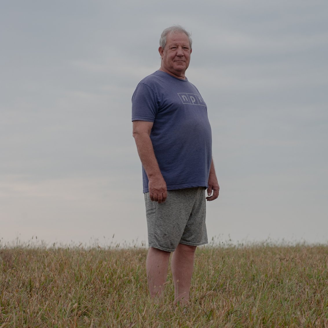 In a grid of four photos, the first one shows a man wearing a T-shirt and shorts standing in a field, and the other three show blackened oil and gas wells. One sticks up near a tree and sits in a circle of black amid a field of grass, one is an elbow of pipe with wet and blackened ground beneath it, and one is a rusty stub of pipe sticking straight up out of the ground.
