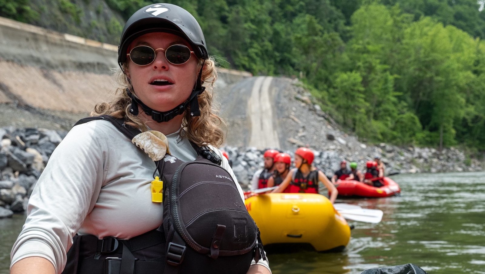 A female river guide leads two groups of rafts down a river