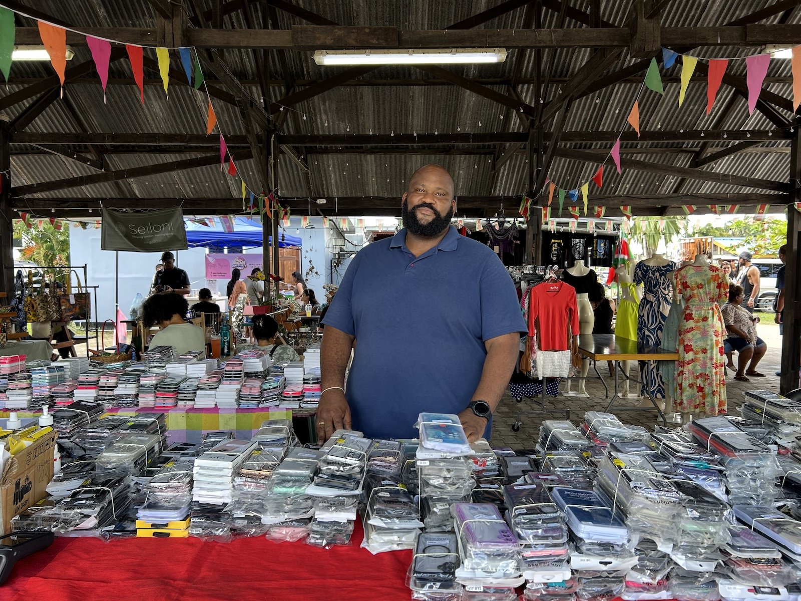 A man stands near a booth at a market