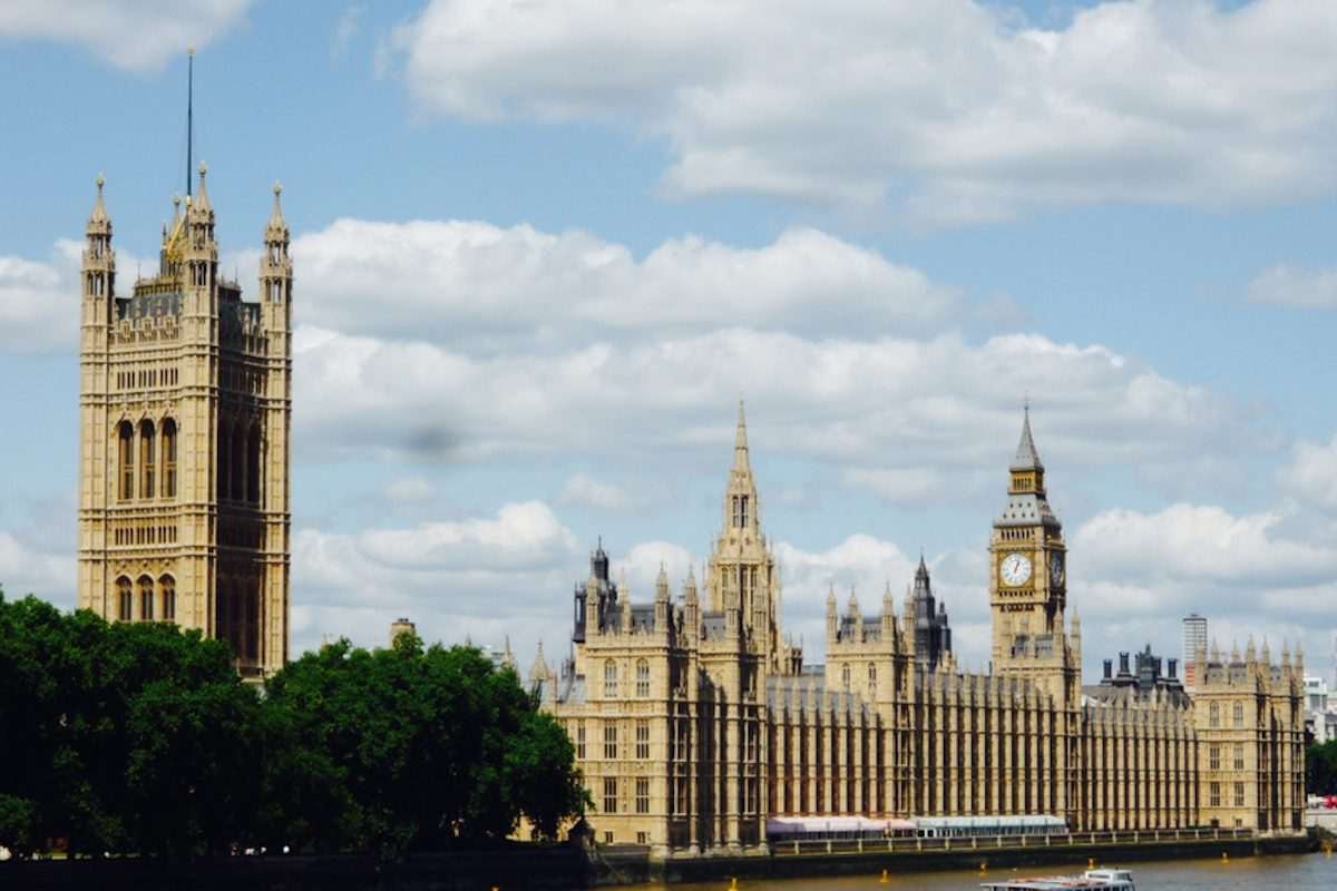 House of Commons and Palace of Westminster seen against blue sky with some clouds
