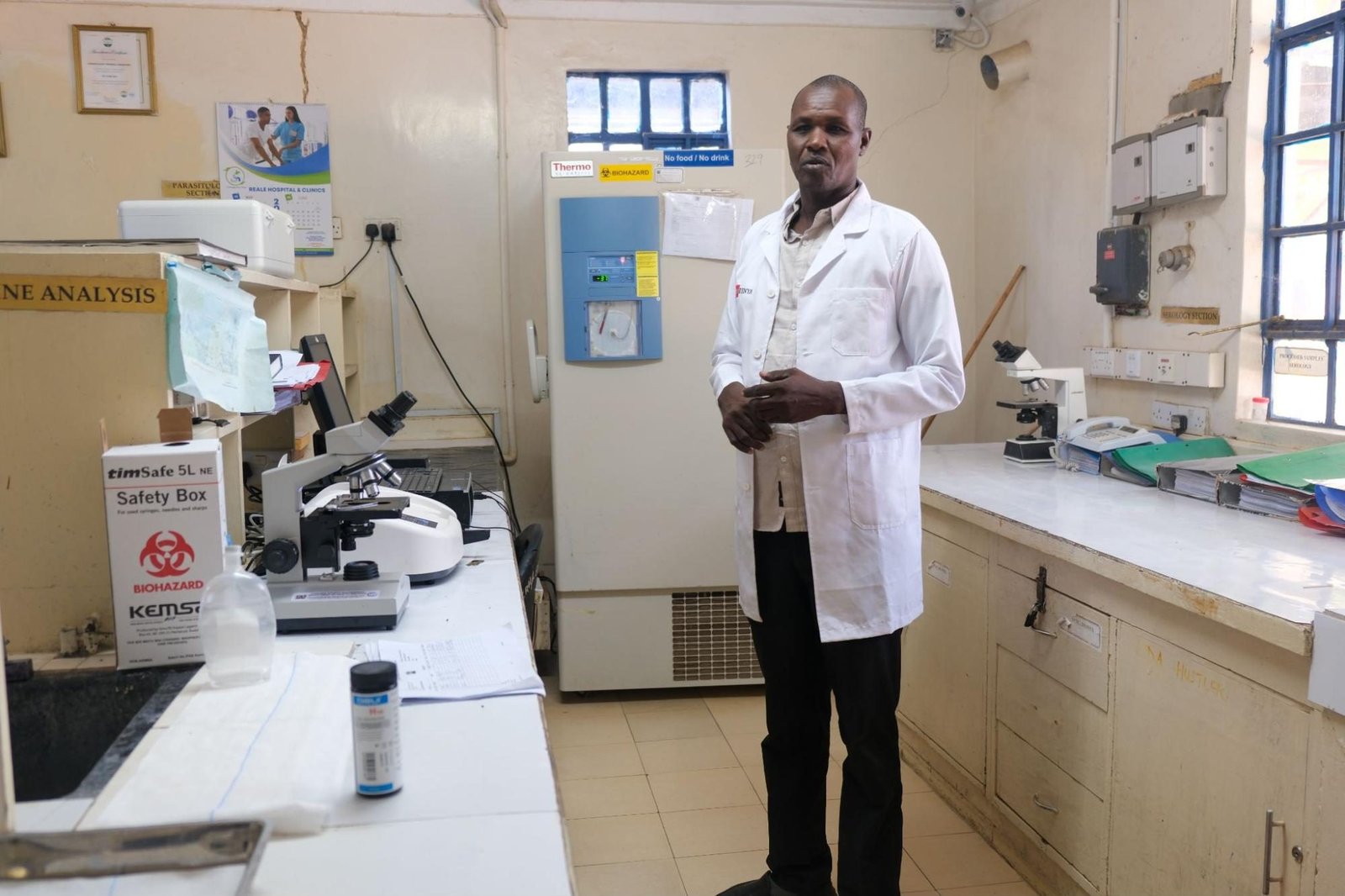 A man in a white doctor's coat stands in a lab