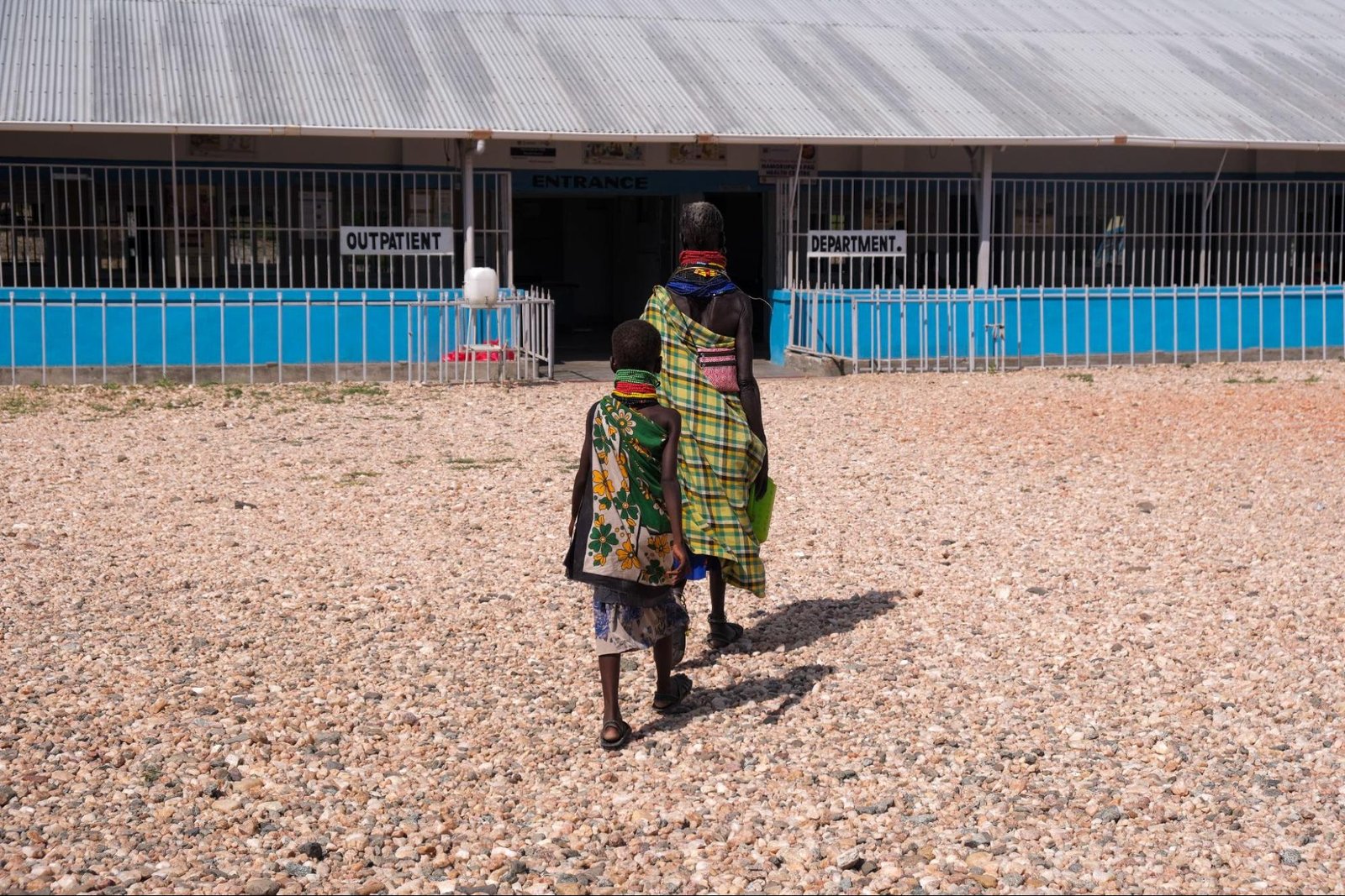 Two people -- a woman and a child -- walk toward a rural clinic