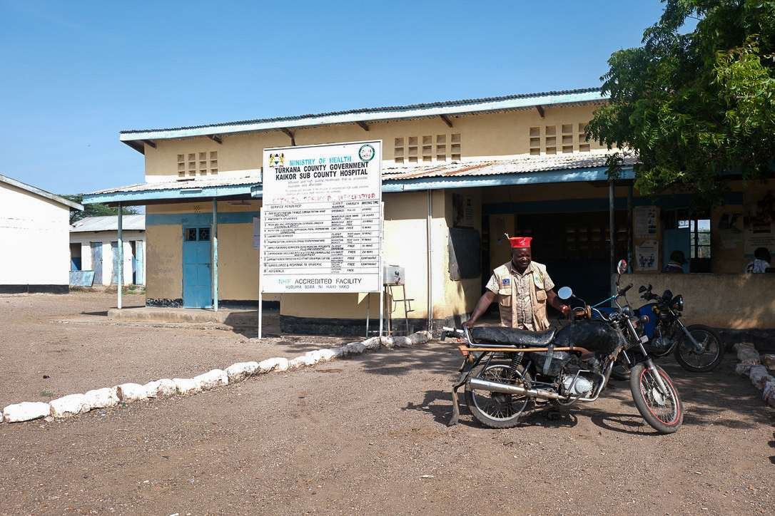 A man stands with his bike in front of a clinic