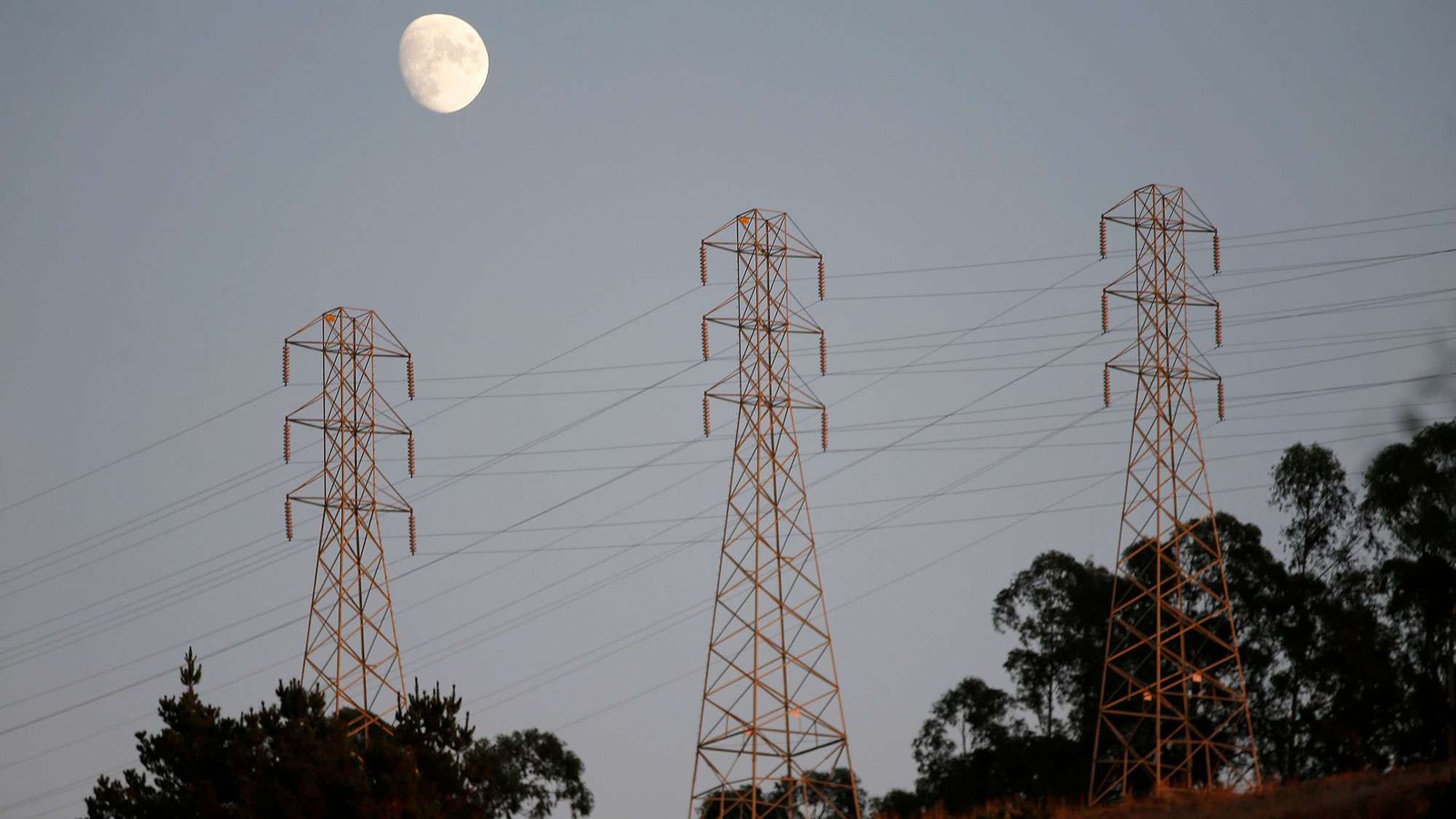Utulity lines are seen in the hills above Oakland as the moon rises above them.