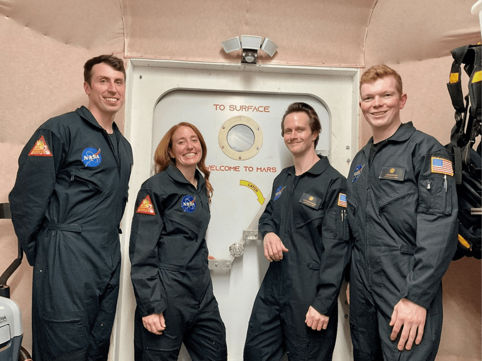 CHAPEA mission 2 crew members (from left) Ross Elder, Ellen Ellis, Matthew Montgomery, and James Spicer, pose in front of the door to the simulated Martian landscape for their first photo inside the CHAPEA habitat after their mission began in October 2025