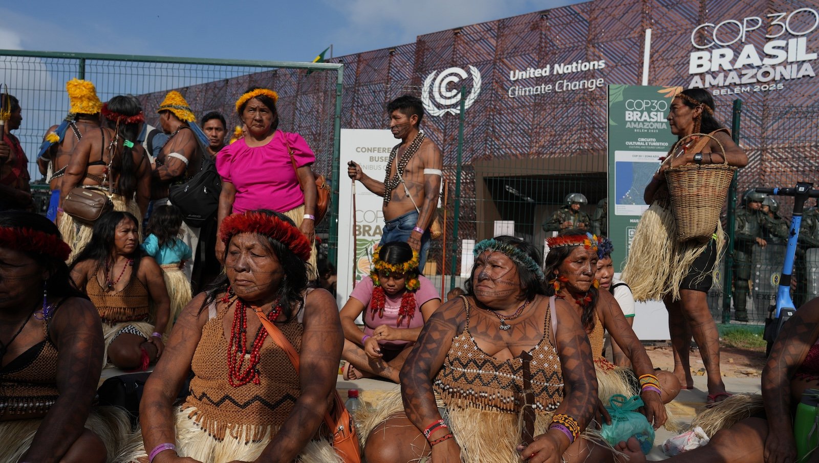 A group of men and women in traditional Indigenous dress stand outside the United Nations climate summit in Brazil