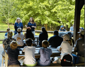 Paige Goff presents to a group in an outdoor park-like setting.