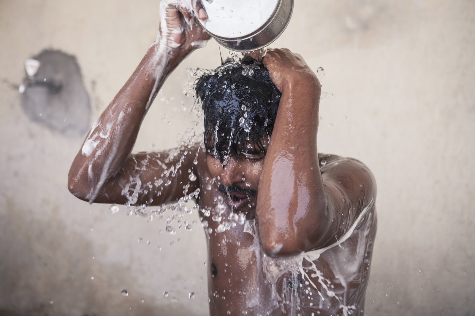 A man dumps water on his head from a basin