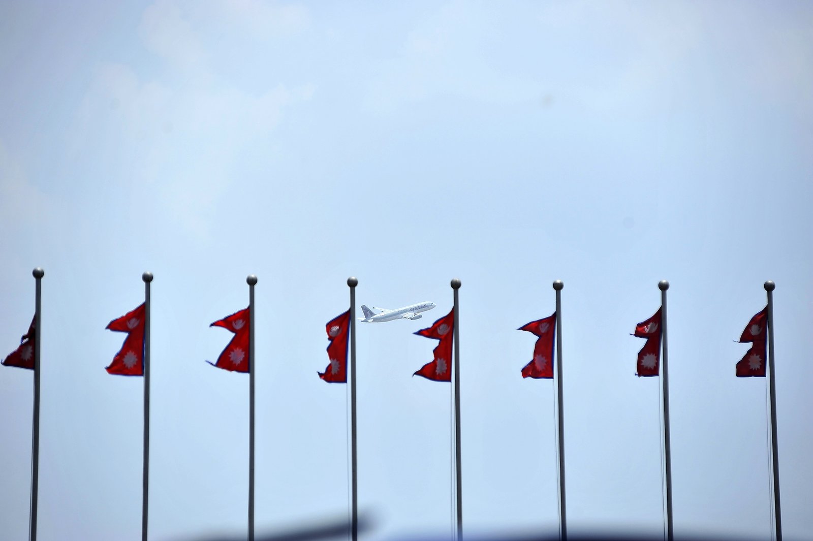 An airplant flies past Nepali flags