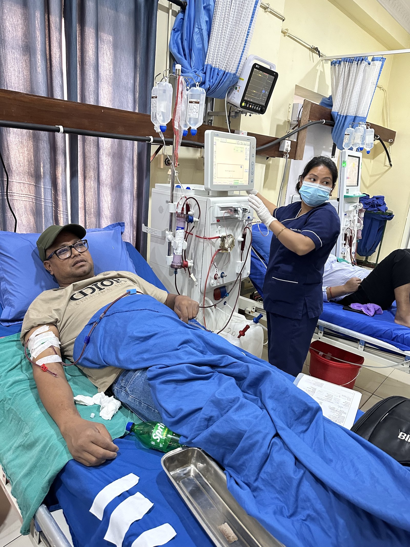 A man on a gurney receives dialysis from a nurse