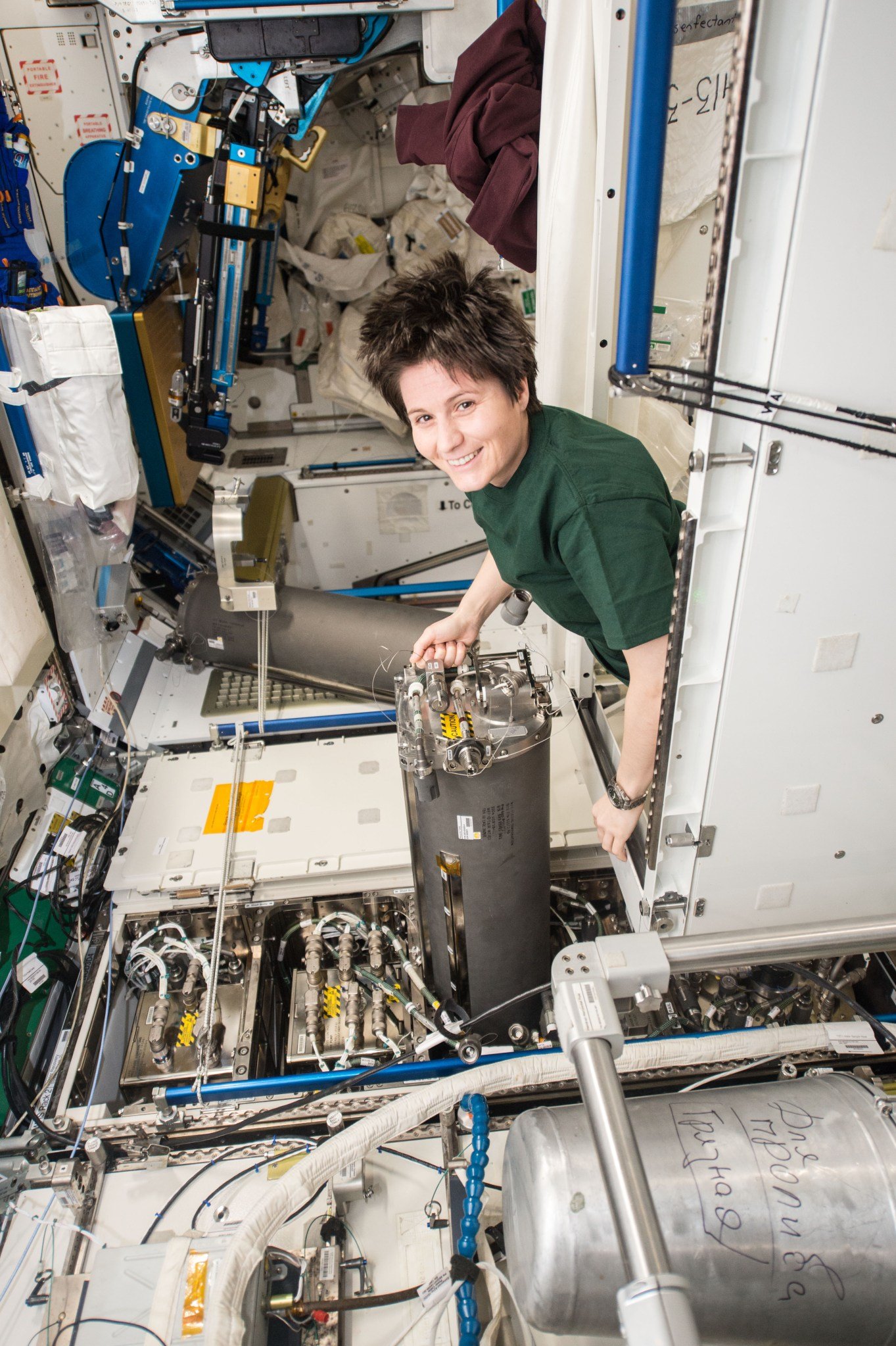 A woman replaces a tank aboard the space station.