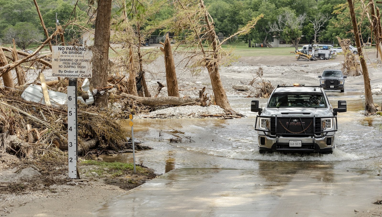 a truck drives though water on a flooded bridge