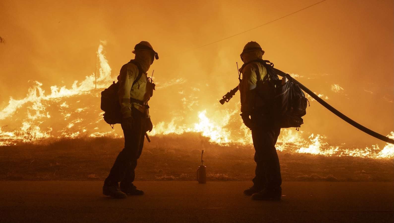 two firefighters look at a wildfire