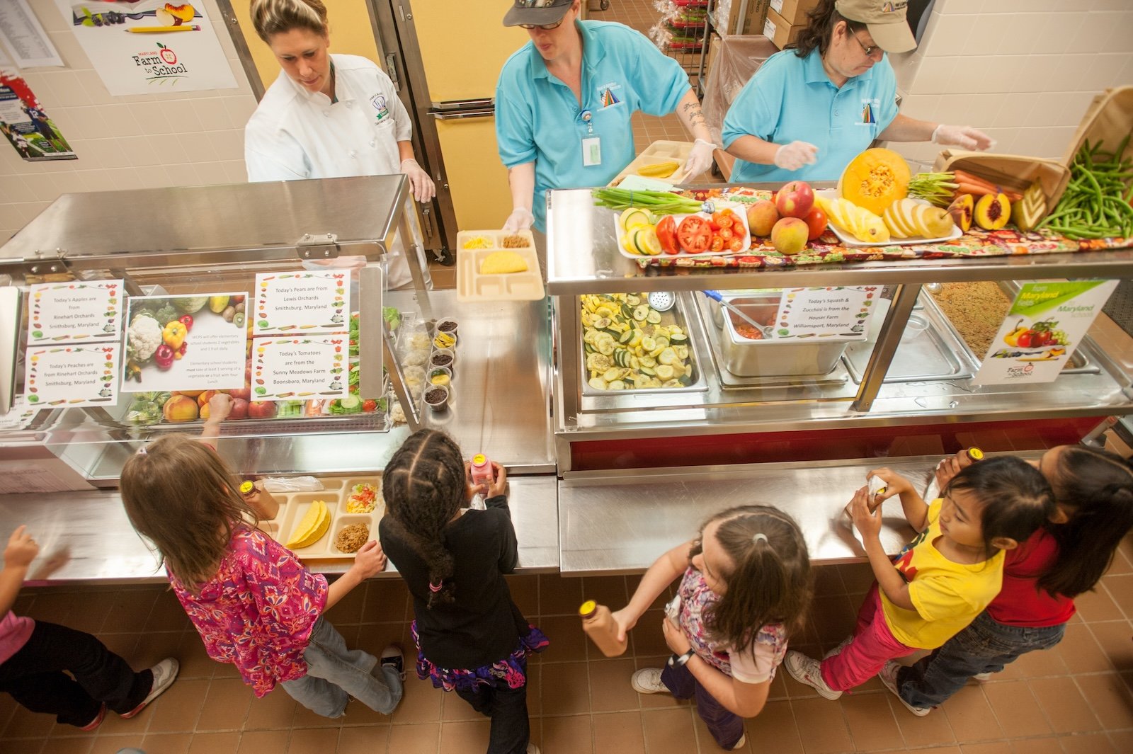 Elementary school children in line at a cafeteria being served healthy lunches
