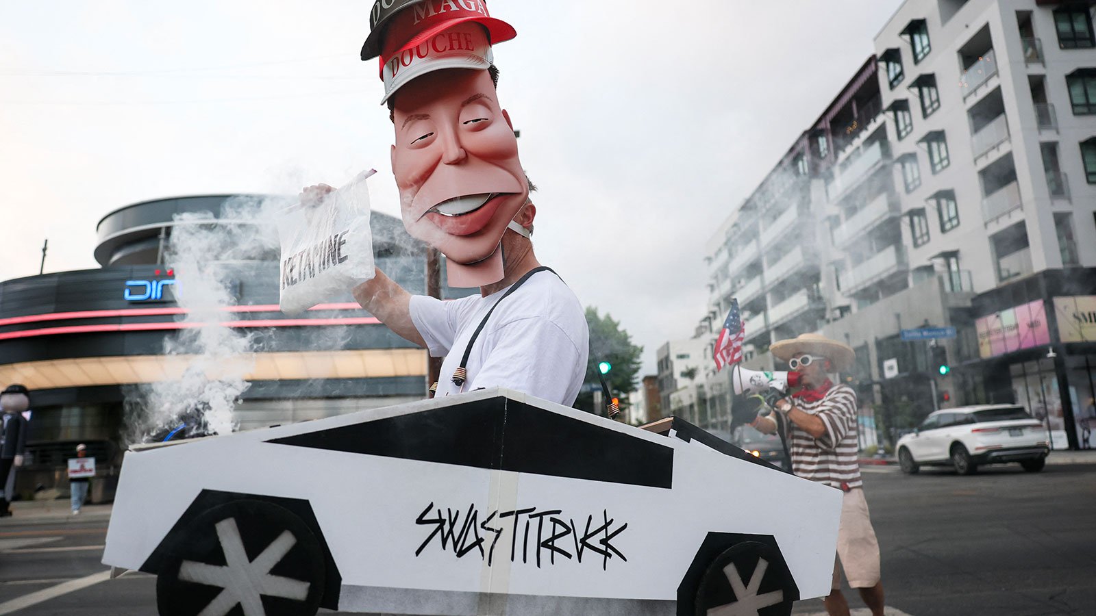 Protestor wearing an Elon Musk mask and a cybertruck sign reading Swastitrukk
