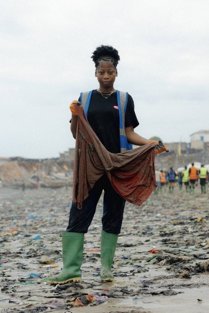 Fideis Issah, a Tide Turners crew member, holding up a piece of clothing found on the shores during weekly cleanup