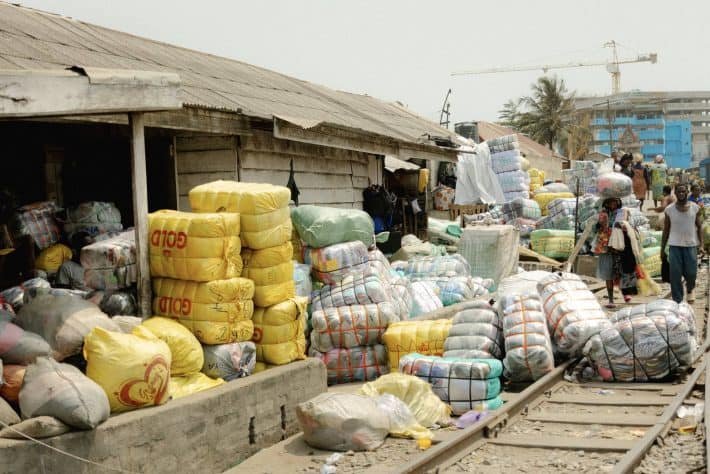 Secondhand clothing bales overflowing from a stall in the Kantamanto Market