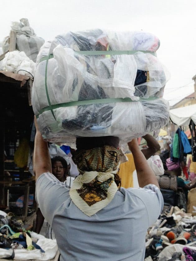 A Kayayei (headporter) carrying a 55kg bale through the Kantamanto market