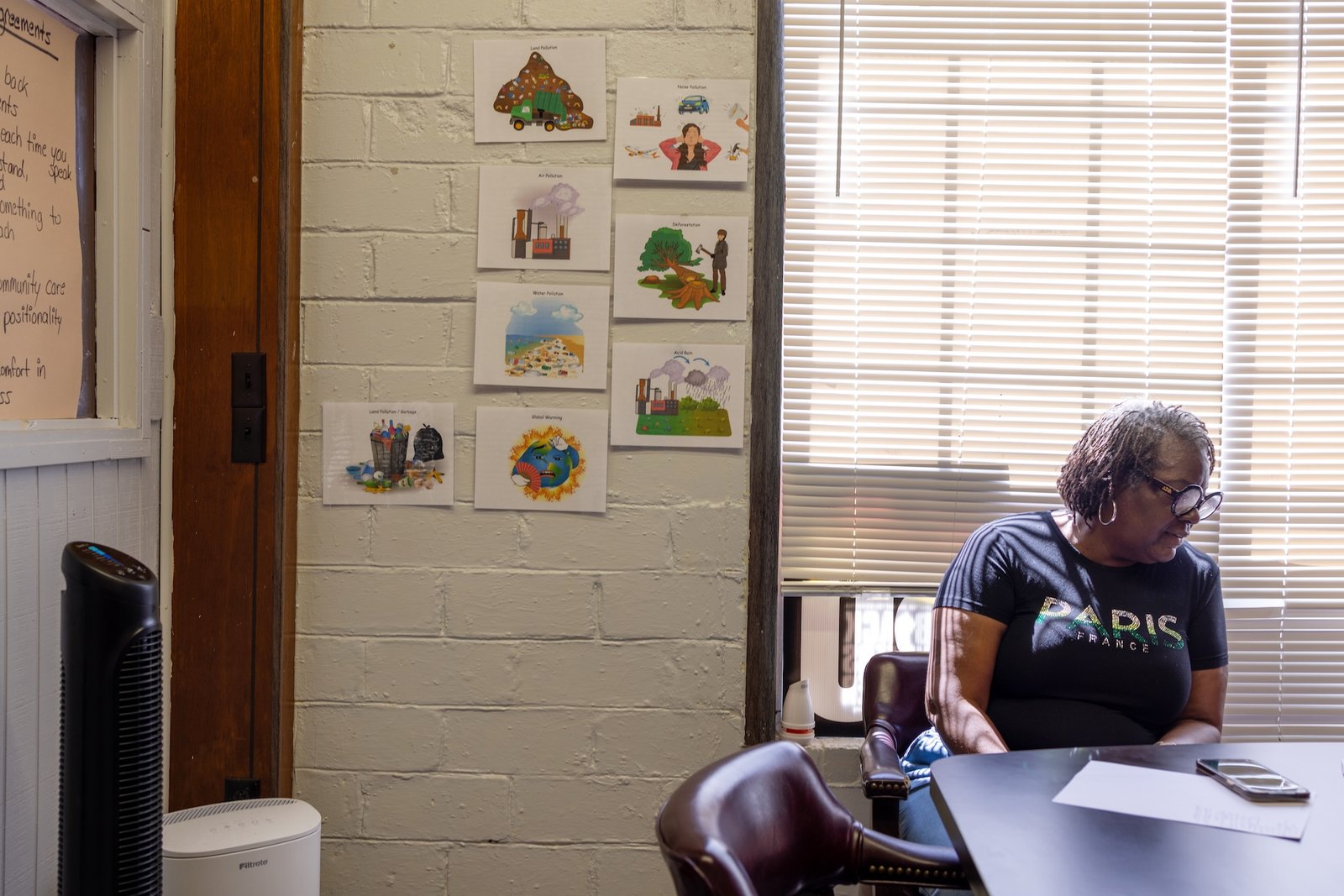 a woman sits near posters depicting health risks from biomass manufacture