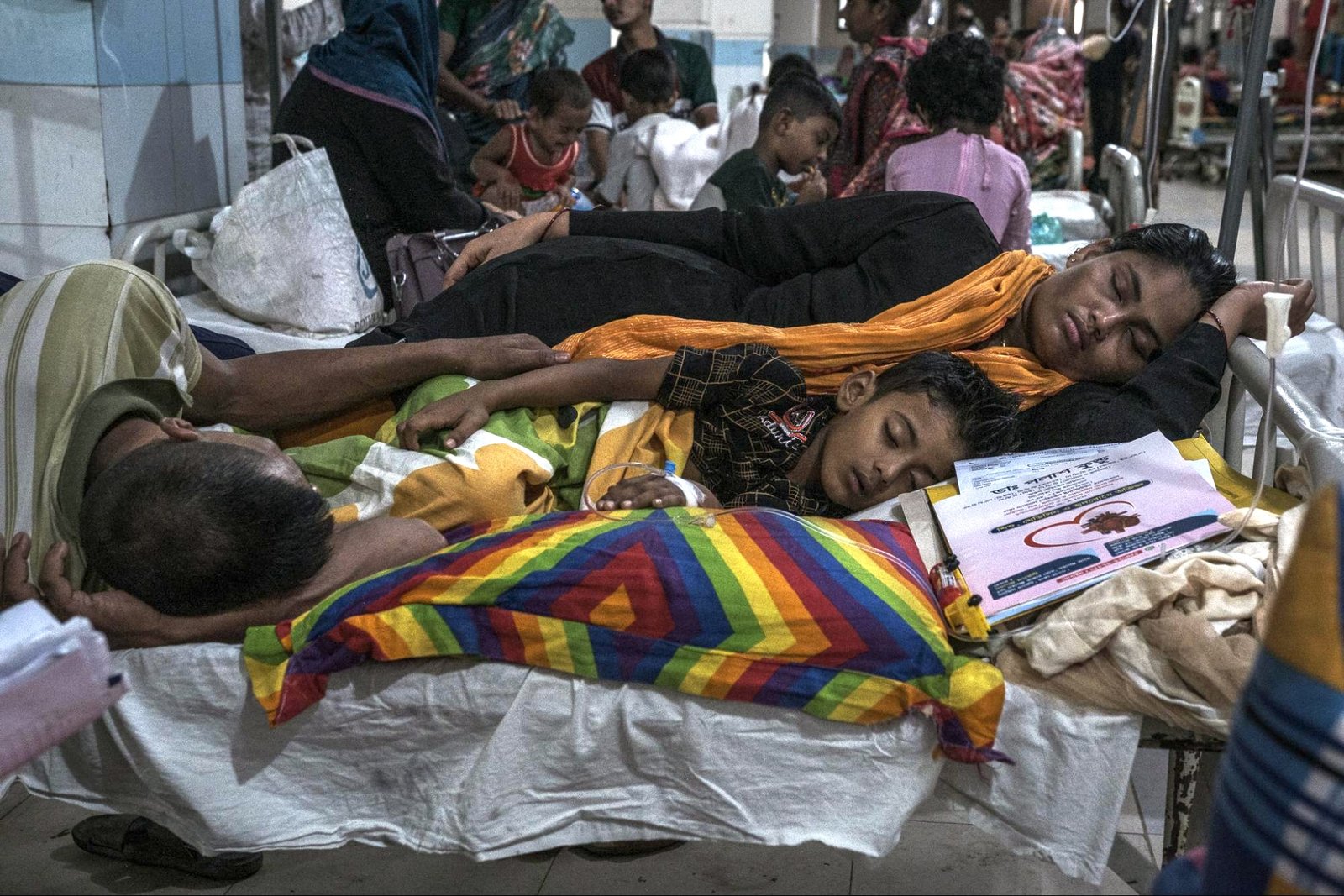 A woman and man lie near a child on a cot in a hospital