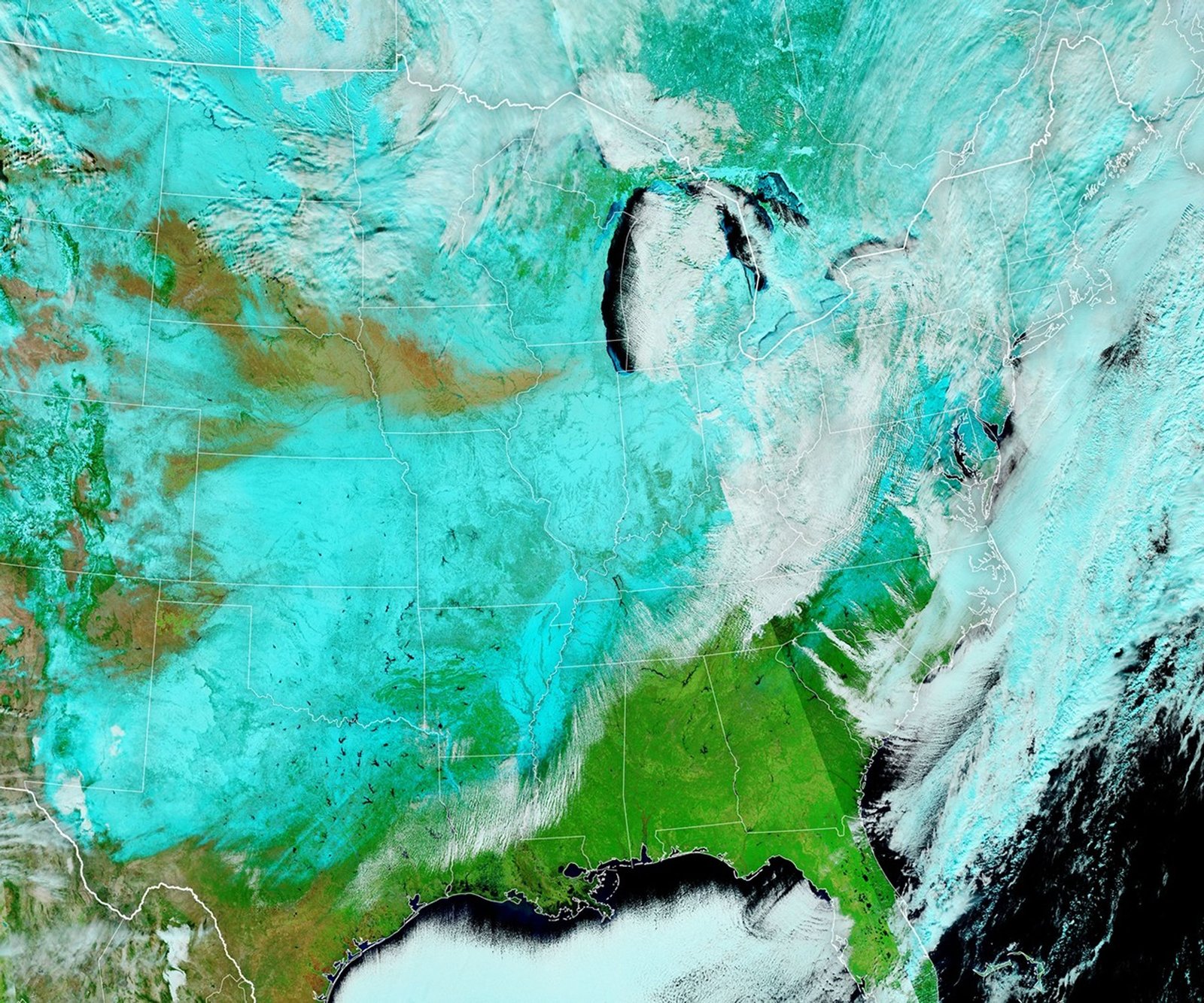 In this false-color satellite image, snow appears blue and covers much of the central, Midwest, and northeast United States. White clouds appear over parts of northeastern states, and the southeast is green with vegetation.