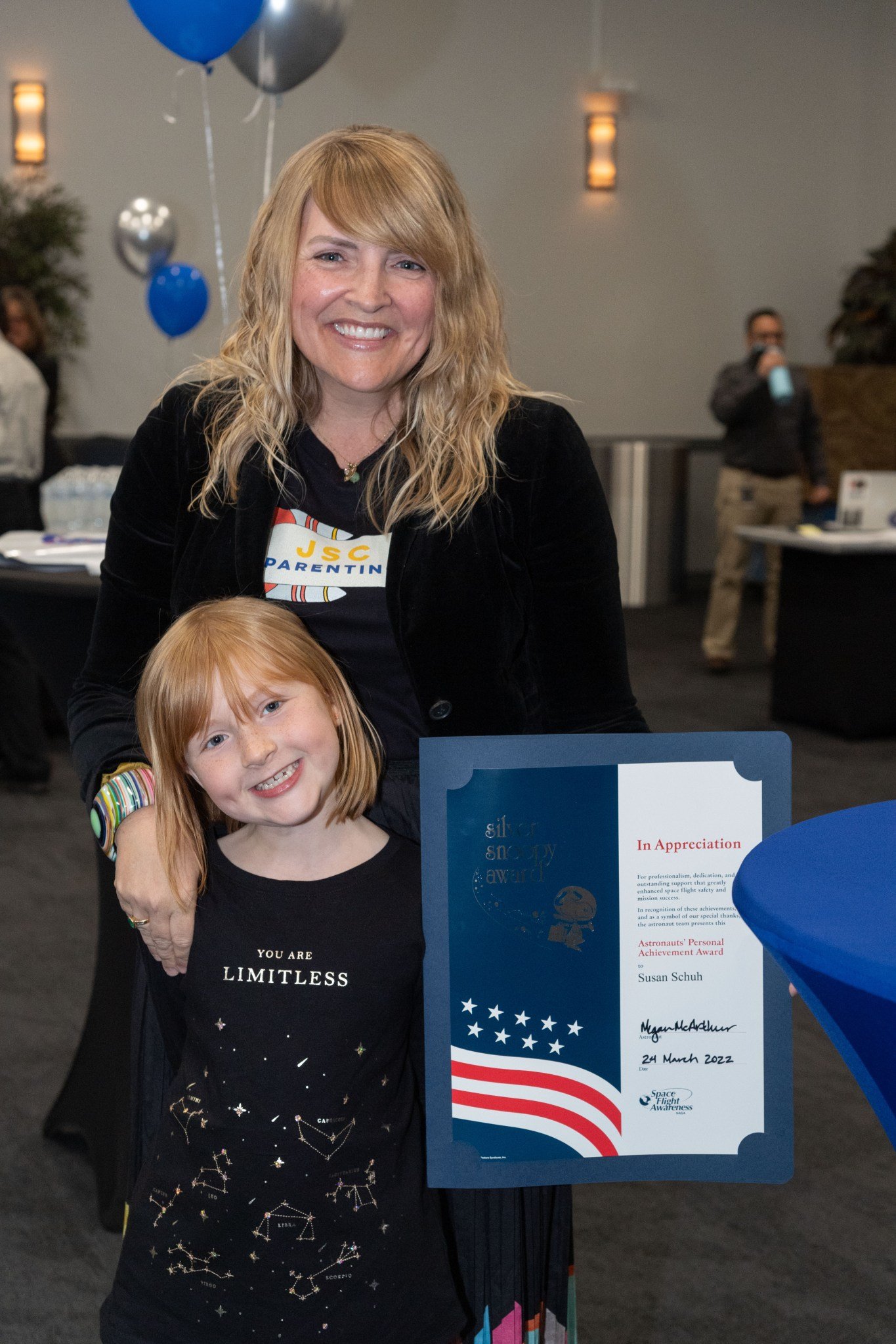 A woman poses with her daughter after accepting an award.