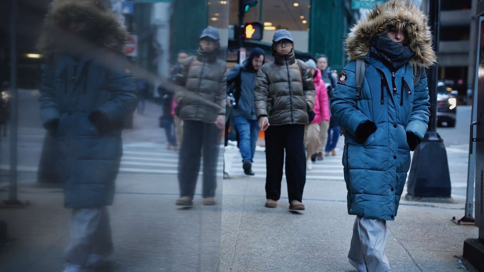 Commuters on a street in downtown Boston brace against the morning cold as a winter storm envelops 230 million Americans.
