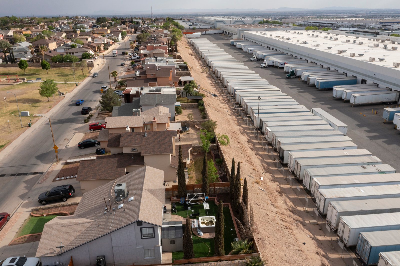 An aerial view of a neighborhood right next to a facility warehouse with lots of trucks