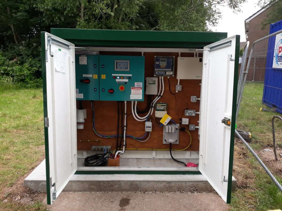 Outdoor electronic equipment cabinet with doors open revealing equipment and components inside, all in an outdoor location