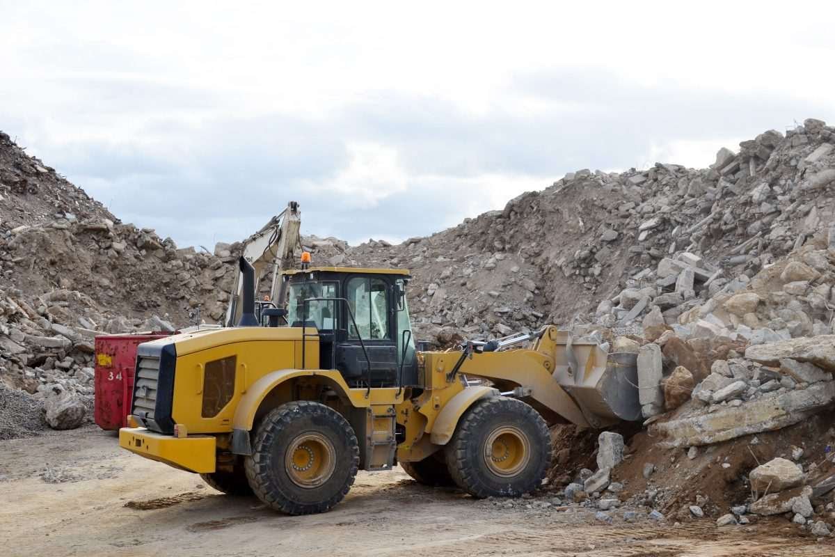Yellow construction vehicle in landscape of mounds of material, such as construction waste