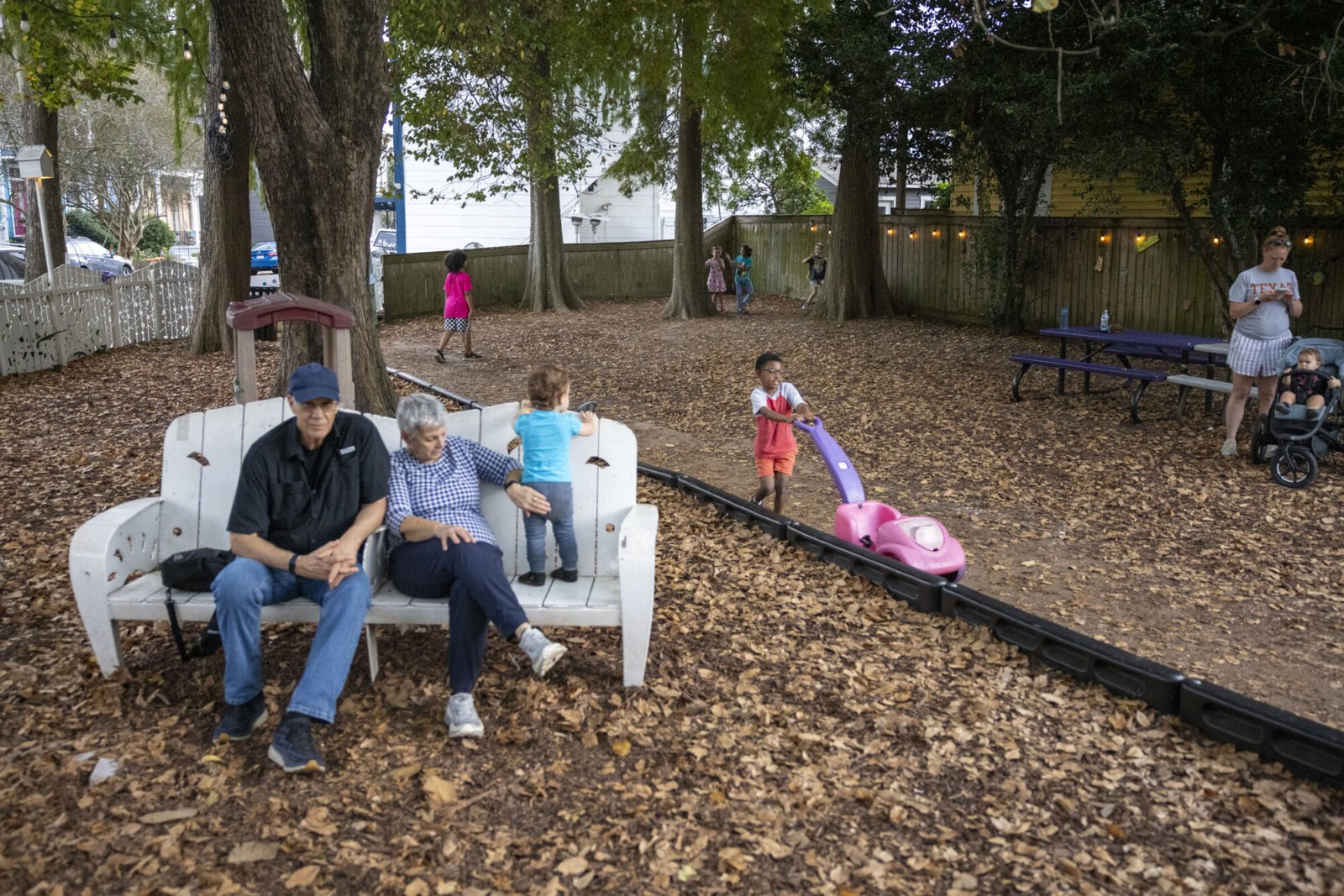 Children and a couple are seen in a shady park