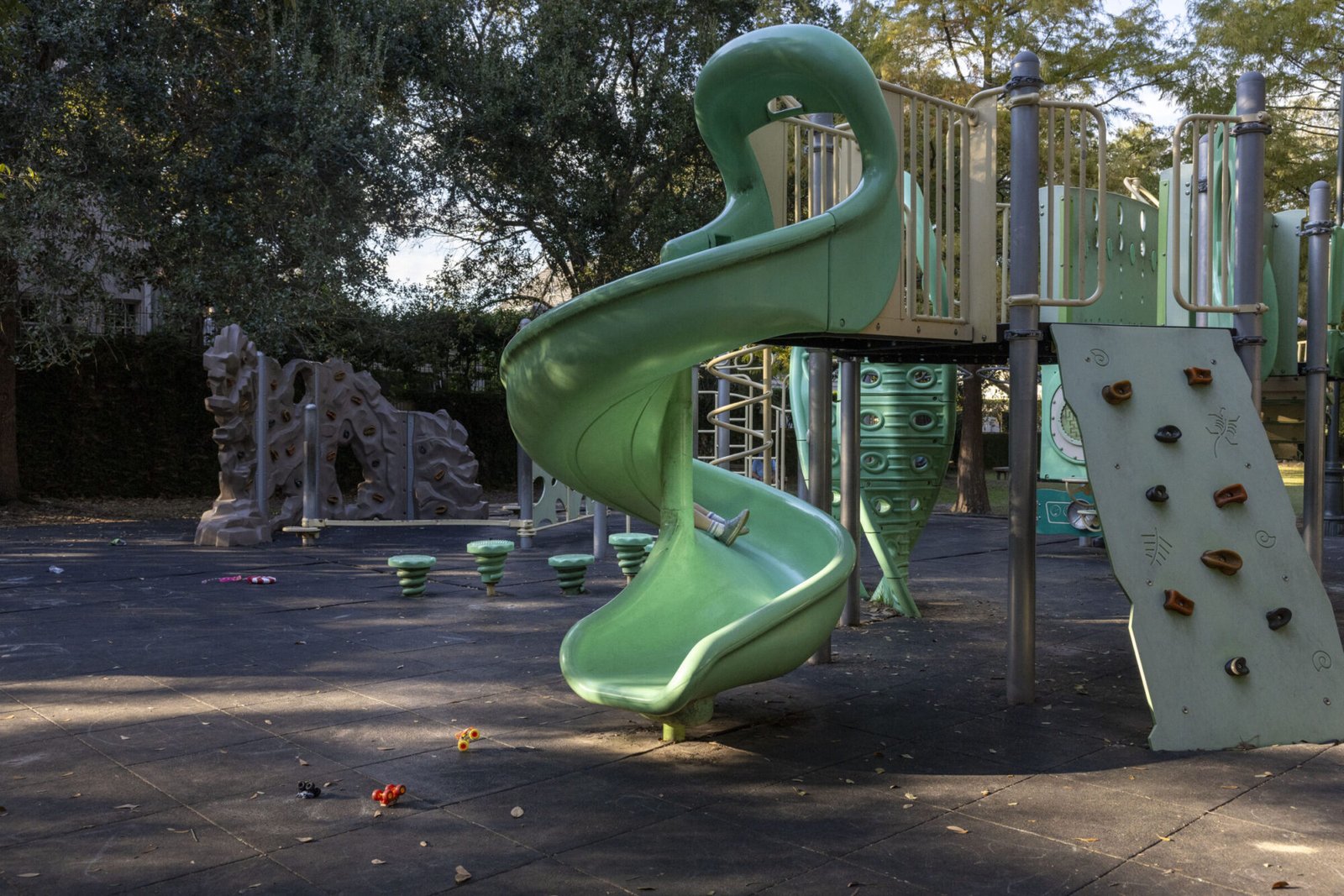 A green twisty slide is seen in a playground