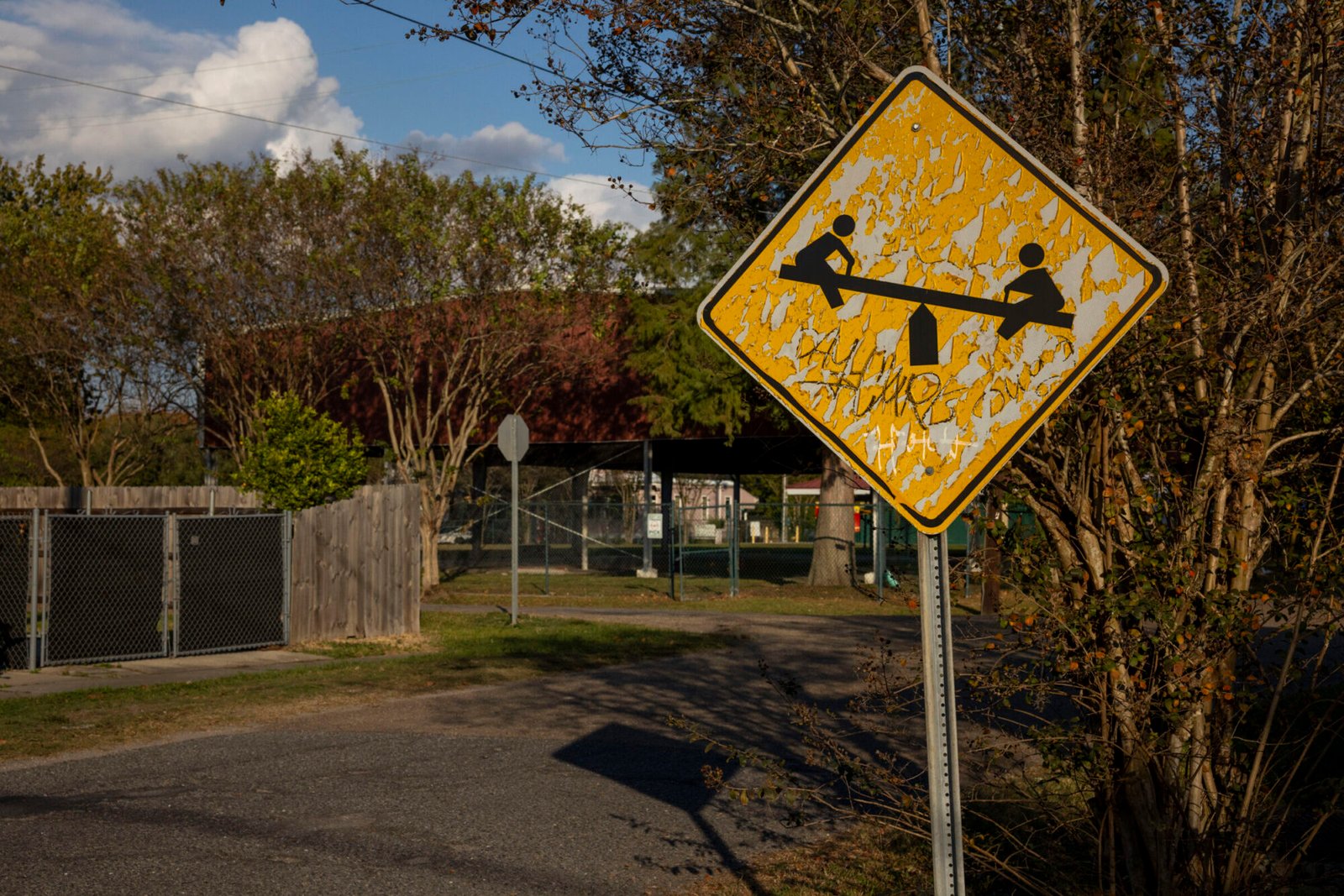 A photo shows a yellow street sign by a park, with an image of children playing on a seesaw