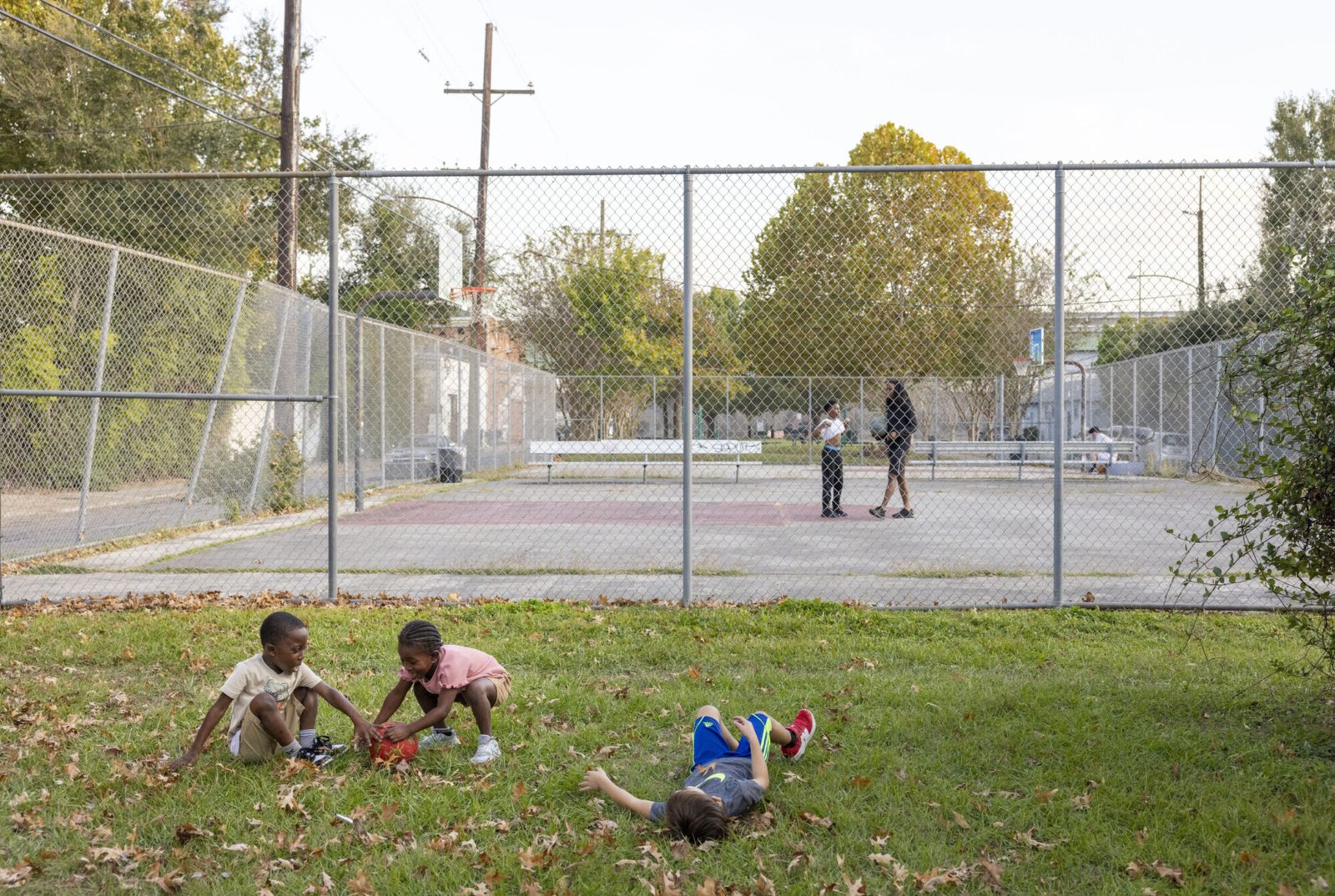 Kids play in the grass in front of a basketball court