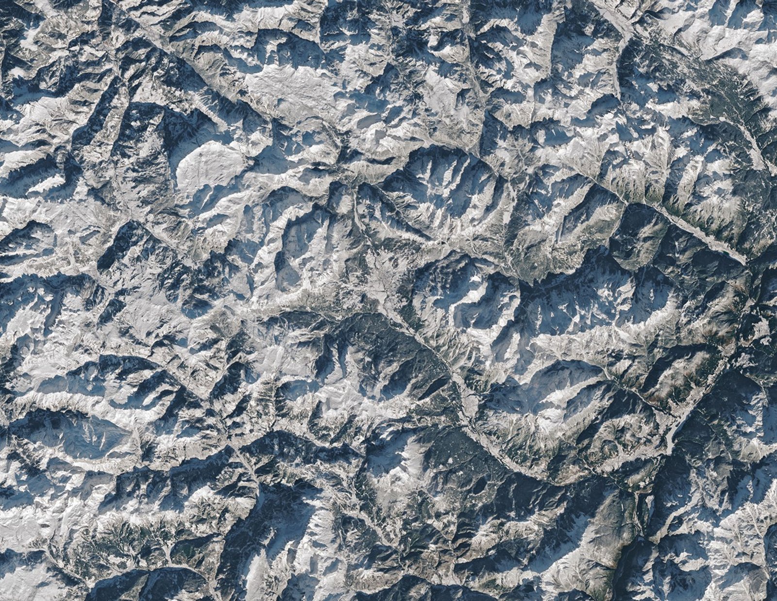 Cortina d’Ampezzo, Italy, co-host city of the 2026 Winter Olympics, sits in a valley surrounded by tall mountains in the Dolomites. Snow covers the ground in most of the scene.