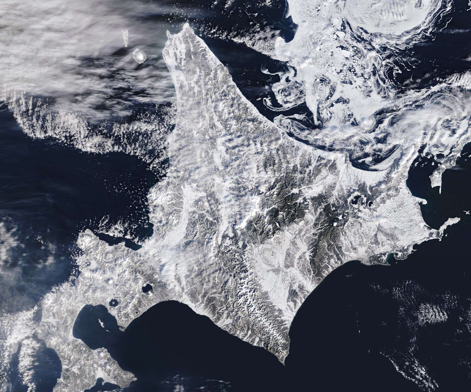 A satellite image shows snow blanketing Hokkaido, Japan, with sea ice swirling just north of the island.