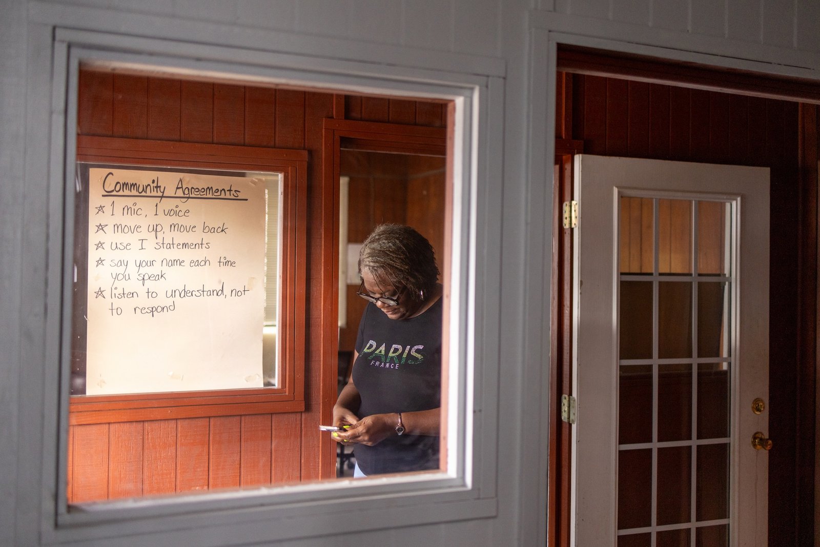 A woman checker her phone in a room with a white board