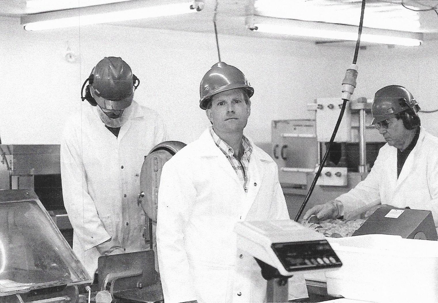 Sam Cobb holds a scale in the RMS Foods factory while two men work behind him