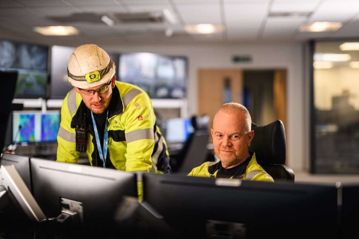 Staff in hi-vis vests look at computer screen in a modern office environment