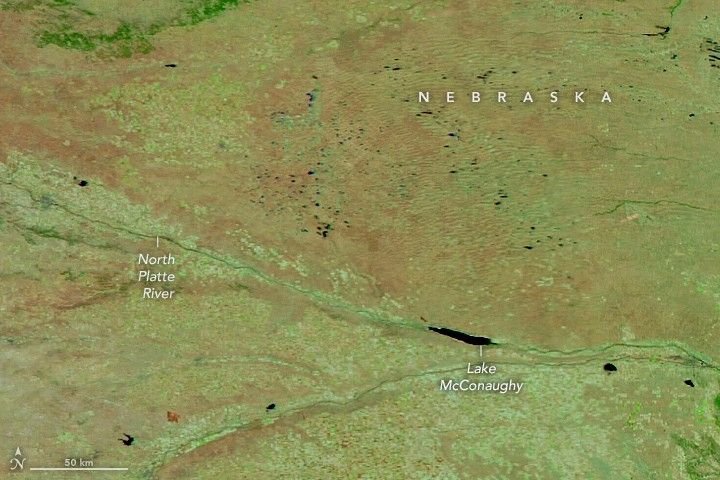 Plains in western Nebraska, divided by the North Platte River, appear in light shades of green and brown in a false-color satellite image.