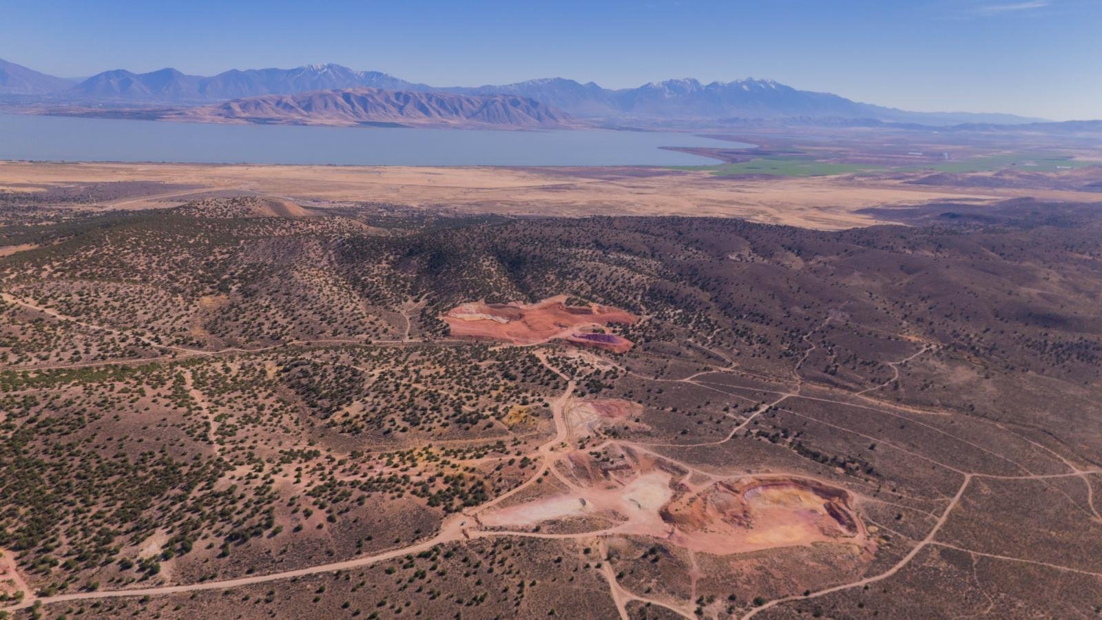 Disturbed earth from mining is visible with a lake and mountains in the background.