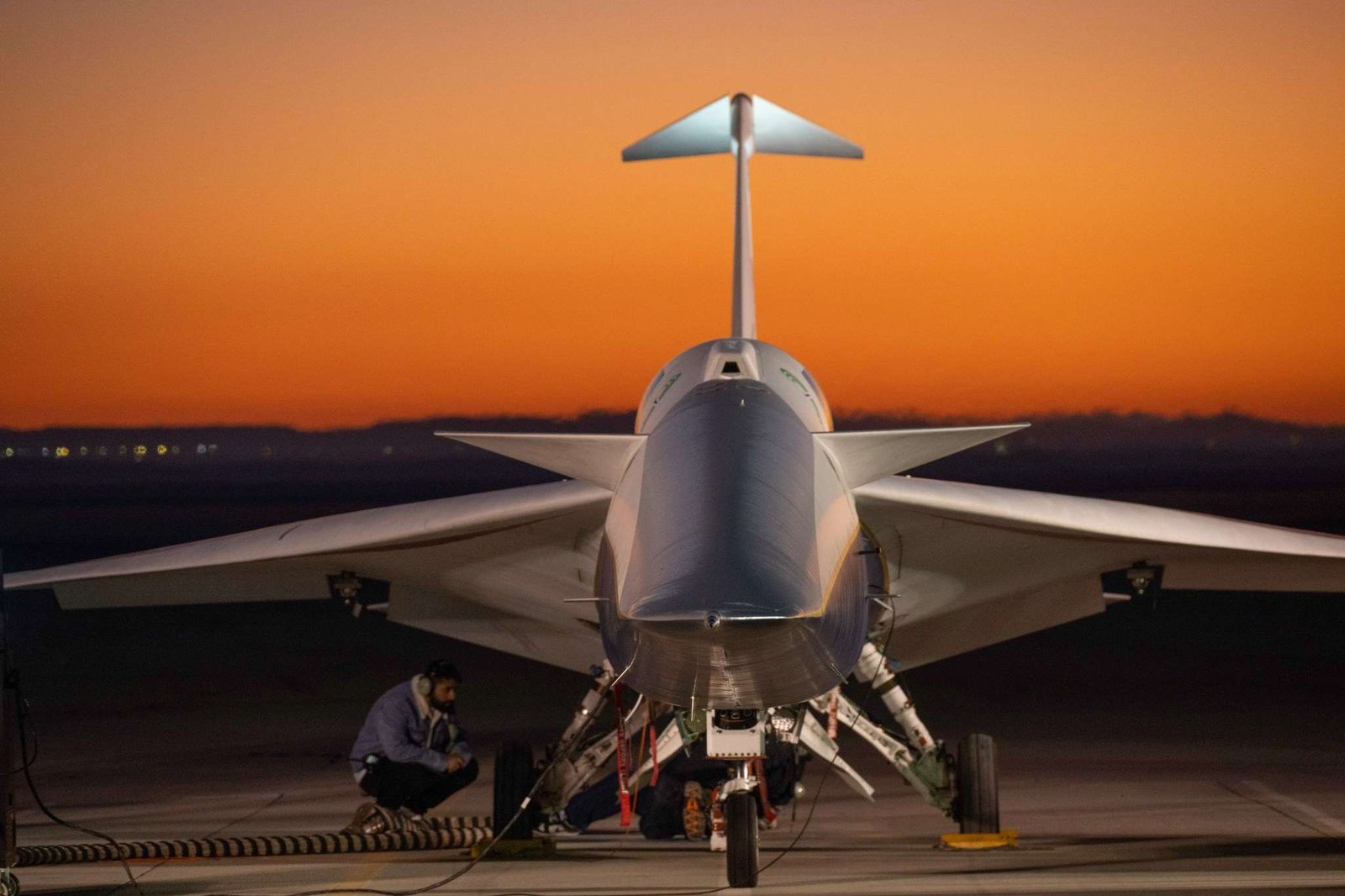 An aircraft resting on a section of runway as seen from the front, with its nose facing the camera. The early morning sky is orange in the background.