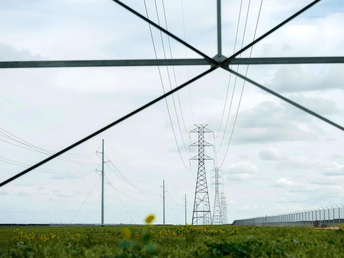 Transmission lines stand in a green field